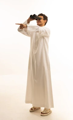 حب الاستكشاف والمغامرة، رؤية الاشياء البعيدة عبر التلسكوب بايماءات الاندهاش والسرور، التخطيط المستقبلي للأهداف والطموحات، بورتريه لرجل عربي خليجي سعودي يرتدي الثوب التقليدي ينظر من خلال منظار الرؤية ثنائي العينين, خلفية بيضاء