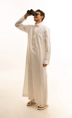 رؤية الاشياء البعيدة عبر التلسكوب بايماءات الاندهاش والسرور، التخطيط المستقبلي للأهداف والطموحات، بورتريه لرجل عربي خليجي سعودي يرتدي الثوب التقليدي ينظر من خلال منظار الرؤية ثنائي العينين, حب الاستكشاف والمغامرة، خلفية بيضاء