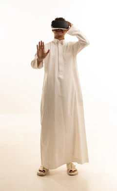 Simulation of the imaginary world, wearing virtual reality glasses, using modern technological devices, a portrait of a Saudi Arabian Gulf man wearing traditional attire and wearing 3D VR glasses, having a good time playing video games, white background.