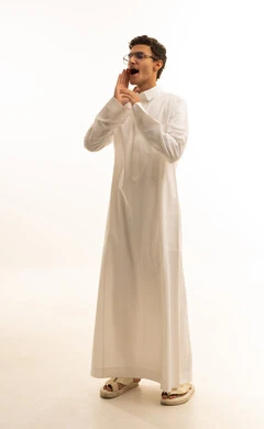 النداء بصوت مرتفع, وضع اليد بجانب الفم لزيادة حدة الأصوات،بورتريه لشاب عربي خليجي سعودي يرتدي الثوب الأبيض ينظر جانباً بإيماءات المناداة لشخص ما، الصراخ والتكلم بنبرة عالية للسماع بشكل جيد، محادثات وتواصل اجتماعي، خلفية بيضاء