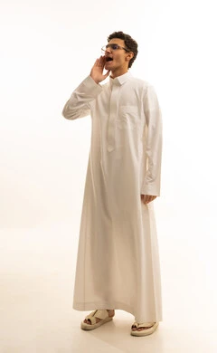 وضع اليد بجانب الفم لزيادة حدة الأصوات،النداء بصوت مرتفع, بورتريه لشاب عربي خليجي سعودي يرتدي الثوب الأبيض ينظر جانباً بإيماءات المناداة لشخص ما، الصراخ والتكلم بنبرة عالية للسماع بشكل جيد، محادثات وتواصل اجتماعي، خلفية بيضاء