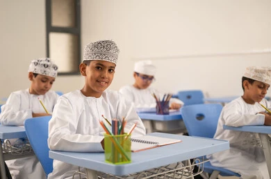 استكمال الواجبات التعليمية، الإستعداد للعام الدراسي الجديد،العودة إلى المدارس، التعليم في سلطنة عمان، مجموعة من الطلاب العربيين الخليجيين العمانيين يرتدون الدشداشة والكمة يجلسون في مقاعدهم ويقومون بحل الواجب