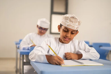 حل الأسئلة والواجبات المدرسية، الإستعداد للعام الدراسي الجديد،العودة إلى المدارس، التعليم في سلطنة عمان، مجموعة من الطلاب العربيين الخليجيين العمانيين يرتدون الدشداشة والكمة يجلسون في مقاعدهم ويقومون بحل الواجب