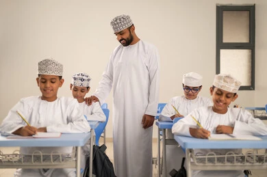 Solve the exam questions with precision and focus, prepare for the new school year, education in the Sultanate of Oman, back to school, a group of Arab Gulf Omani students sitting in their seats with their teacher.