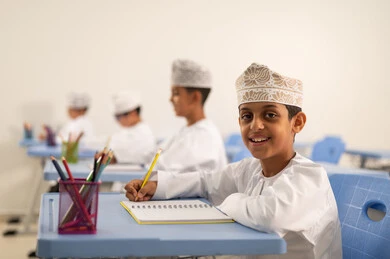 إنجاز مهام الدروس اليومية ، الإستعداد للعام الدراسي الجديد،العودة إلى المدارس، التعليم في سلطنة عمان، مجموعة من الطلاب العربيين الخليجيين العمانيين يرتدون الدشداشة والكمة يجلسون في مقاعدهم ويقومون بحل الواجب