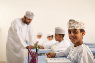 جودة التعليم في سلطنة عمان، المشاركة الفعالة للطلاب مع المدرسين، معلم عربي خليجي عماني يرتدي الدشداشة والكمة يقوم بمناقشة الدروس مع طلابه، التربية والتعليم بالمناهج المقررة للتلاميذ، حوارات ودية بين الاستاذ والطلاب