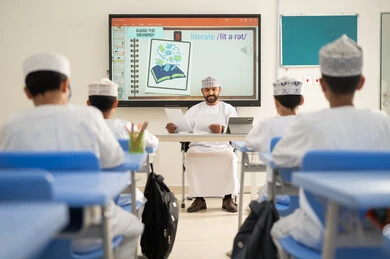 الارتقاء بالمعرفة العلمية ودعم الإبداع، متابعة مجموعة من الطلاب داخل الفصل، معلم عربي خليجي عماني يرتدي الدشداشه والكمه يشرح لطلابه في بيئه مدرسيه تعليميه متطوره، نظام التعليم الحديث، جودة التعلم في المدارس الأكاديميه