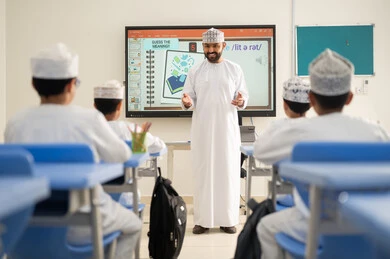 Supporting scientific creativity and skill development, monitoring a group of students inside the classroom, an Arab Gulf Omani teacher wearing a dishdasha and kumma explaining to his students in an advanced educational school environment, the modern education system, the quality of learning in academic schools. Supporting scientific creativity and skill development, monitoring a group of students inside the classroom, an Arab Gulf Omani teacher wearing a dishdasha and kumma explaining to his students in an advanced educational school environment, the modern education system, the quality of learning in academic schools.