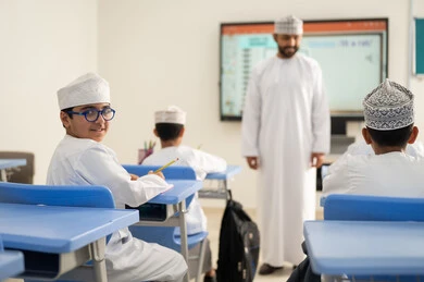 دعم العلوم وتنمية مهارات الابتكار، متابعة مجموعة من الطلاب داخل الفصل، معلم عربي خليجي عماني يرتدي الدشداشه والكمه يشرح لطلابه في بيئه مدرسيه تعليميه متطوره، نظام التعليم الحديث، جودة التعلم في المدارس الأكاديميه