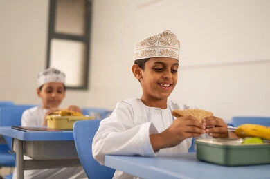 Eating nutritious foods between lessons, the back-to-school season, meals and snacks rich in essential nutrients for building the body, a group of Arab Gulf Omani students wearing the dishdasha and kumma are sitting in their seats with lunch boxes in front of them. Eating nutritious foods between lessons, the back-to-school season, meals and snacks rich in essential nutrients for building the body, a group of Arab Gulf Omani students wearing the dishdasha and kumma are sitting in their seats with lunch boxes in front of them.