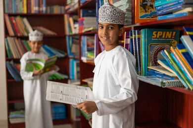 استغلال وقت الفراغ في التعلم، حب الاطلاع والمعرفة، طالبان عربيان خليجيان عمانيان يرتديان الدشداشة و الكمة يقومان بقراءة كتب مدرسية، التعليم والدراسة في سلطنة عمان, تنمية مهارة القراءة للطلاب, زيارة مكتبة المدرسة