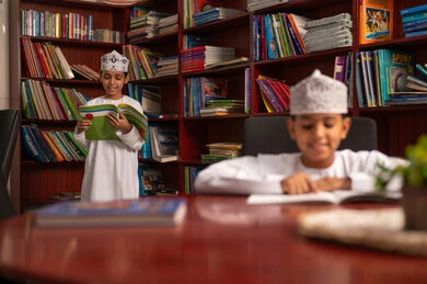تنمية مهارة القراءة للطلاب, حب الثقافة والاستطلاع، قضاء وقت الفراغ بالتعلم والتثقف الذاتي، زيارة مكتبة المدرسة، طالبان عربيان خليجيان عمانيان يرتديان الدشداشة و الكمة يقومان بقراءة الكتب، التعليم والدراسة في سلطنه عمان، الاهتمام بتصفح الكتب المفيدة