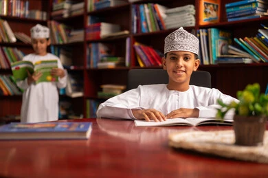 Spending free time learning and self-education, visiting the school library, loving culture and exploration, two Arab Gulf students from Oman wearing the dishdasha and kumma are reading books, education and study in the Sultanate of Oman, developing reading skills for students, and focusing on browsing useful books.