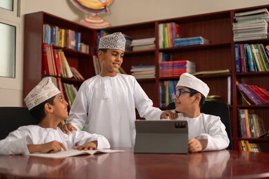 مناقشة المواد الدراسيه، تنمية القدرات الذهنية من خلال التعلم، استخدام التابلت فى الدراسة، مفهوم الاجتهاد وطلب التفوق، التربية والتعليم في سلطنه عمان، مجموعه من الطلاب العربيون الخليجيون العمانيون يرتدون الدشداشة والكمة يجلسون داخل مكتبه المدرسة
