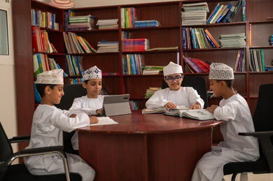 أهمية العلم في تنمية القدرات العقلية، حل الواجبات المدرسية، مفهوم الاجتهاد وطلب التفوق، التربية والتعليم في سلطنه عمان، مجموعه من الطلاب العربيون الخليجيون العمانيون يرتدون الدشداشة والكمة يجلسون داخل مكتبه المدرسة، استخدام التابلت فى الدراسة