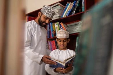 قضاء وقت ممتع ، الحوارات الودية بين المعلم والطالب ، تلميذ عربي خليجي عماني يرتدي الدشداشة و الكمة يقف امام مكتبة خشبية، الاستمتاع بقراءة الكتب المدرسية، تأدية الواجبات المدرسية، التعليم في سلطنه عمان قضاء وقت ممتع ، الحوارات الودية بين المعلم والطالب ، تلميذ عربي خليجي عماني يرتدي الدشداشة و الكمة يقف امام مكتبة خشبية، الاستمتاع بقراءة الكتب المدرسية، تأدية الواجبات المدرسية، التعليم في سلطنه عمان