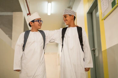 تعزيز الروابط الودية بين الطلاب، الإستعداد للفصل الدراسي الجديد، وقت اللعب والترفيه ، طالبان عربيان خليجيان يرتديان الدشداشة و الكمة و الحقيبة المدرسية يخرجان الى بهو المدرسه, ايماءات السعاده والمرح, مدارس أكاديميه في سلطنة عمان تعزيز الروابط الودية بين الطلاب، الإستعداد للفصل الدراسي الجديد، وقت اللعب والترفيه ، طالبان عربيان خليجيان يرتديان الدشداشة و الكمة و الحقيبة المدرسية يخرجان الى بهو المدرسه, ايماءات السعاده والمرح, مدارس أكاديميه في سلطنة عمان