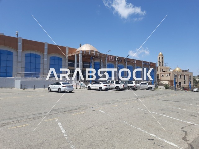 المباني والمحلات التجارية، الطرقات الاسفلتية المعبدة في الأماكن الجبلية في وقت النهار، طريق معبد في منطقة الباحة، أعمدة الإنارة الطرقية، حركة مرور السيارات في الشوارع