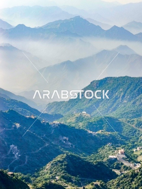 A place and natural tourist area, the old popular houses on the mountains of Faifa in Jazan, southern Saudi Arabia, the peaks and rocky elevations during the day, the trees and plants, and the green natural spaces, the agricultural terraces on the mountain slopes.