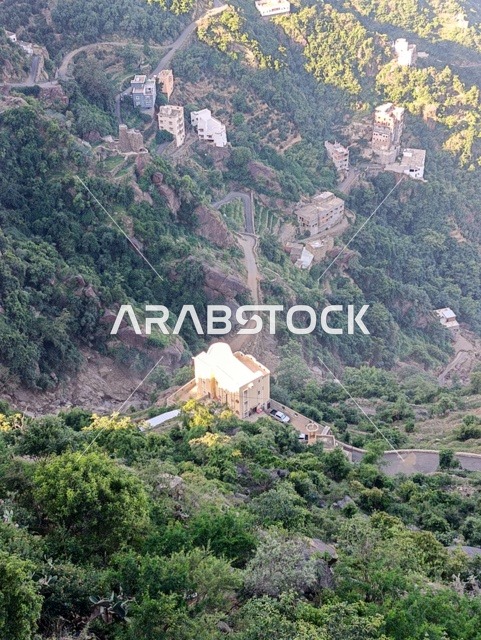 The old traditional houses on the mountains of Faifa in Jazan, southern Saudi Arabia, the peaks and rocky elevations during the day, a natural tourist place and area, the trees and plants and areas of green nature, the agricultural terraces on the mountain slopes.
