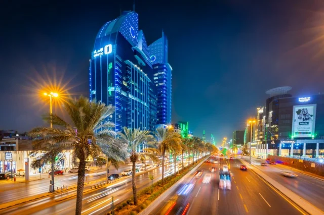 The growth and urban development in the modern and advanced style of towers and skyscrapers in the Kingdom of Saudi Arabia, the architectural engineering art of a lit tower in Riyadh at night, famous landmarks and commercial, economic, and tourist buildings in the capital, the architectural engineering art of the facilities.