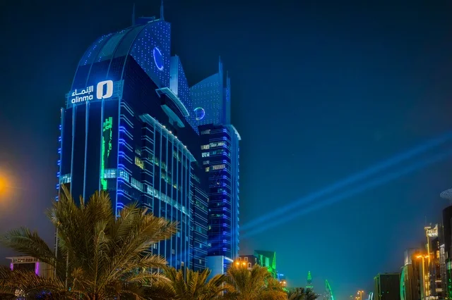 The architectural engineering art of structures, the growth and urban development in the modern and advanced style of towers and skyscrapers in the Kingdom of Saudi Arabia, the architectural engineering art of a lit tower in the city of Riyadh at night, famous landmarks and commercial, economic, and tourist buildings in the capital.