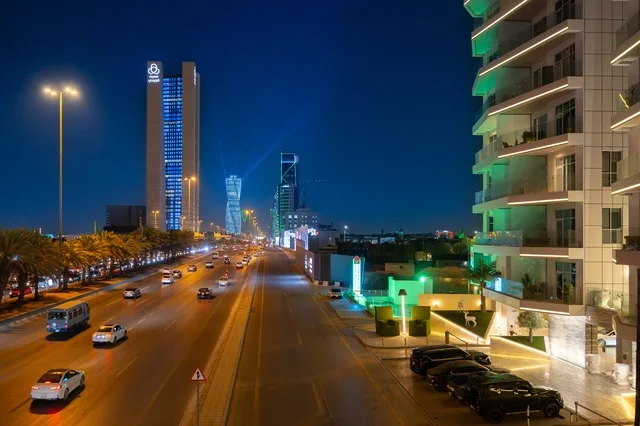 Famous landmarks and commercial, economic, and tourist buildings in the capital, the architectural engineering art of the facilities, urban growth and development in the modern and advanced style of towers and skyscrapers in the Kingdom of Saudi Arabia, the architectural engineering art of a lit tower in the city of Riyadh at night.
