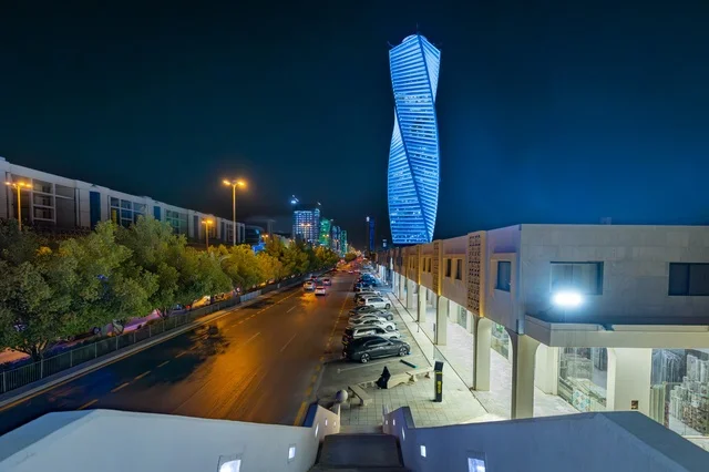 Traffic on a major street, the architectural engineering art of a lit tower in Riyadh at night, famous commercial, economic, and tourist landmarks in the capital, the architectural engineering art of facilities, urban growth and development in the modern and advanced style of towers.