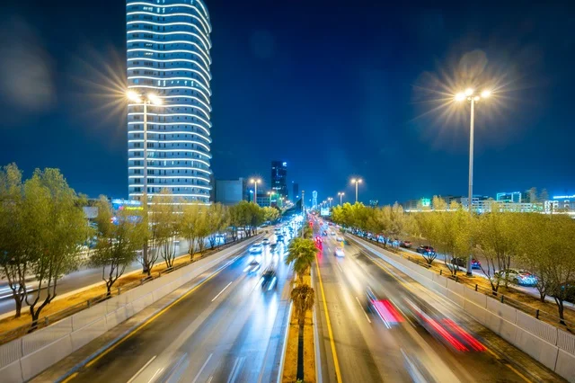Traffic on a major street, the architectural engineering art of a lit tower in Riyadh at night, famous commercial, economic, and tourist landmarks in the capital, the architectural engineering art of facilities, urban growth and development in the modern and advanced style of towers.