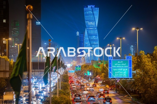 علم المملكة راية التوحيد الخضراء، لوحات طرقية زرقاء، الفن الهندسي المعماري لبرج مضاء في مدينة الرياض في وقت الليل، معالم تجارية واقتصادية وسياحية مشهورة في العاصمة، الفن الهندسي المعماري للمنشآت، النمو والتطور العمراني على الطراز الحديث والمتطور للأبراج