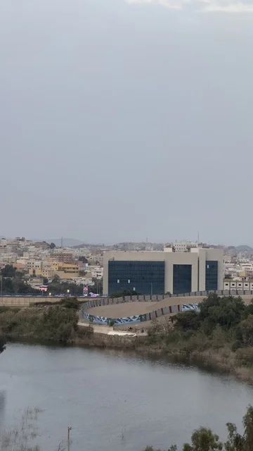 A calm water surface, spending enjoyable time on recreational tourist trips, famous tourist places and landmarks, areas of peaks and mountainous elevations, the natural landscapes in Abha in the Asir region of the Kingdom of Saudi Arabia, the mountains of Abha covered with clouds and mist, trees and green plants.