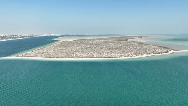 The coastal nature and turquoise waters, the harmony of green spaces with sandy beaches, aerial drone photography of Al-Huwailat Island in Jubail City, tourist marine atmosphere.