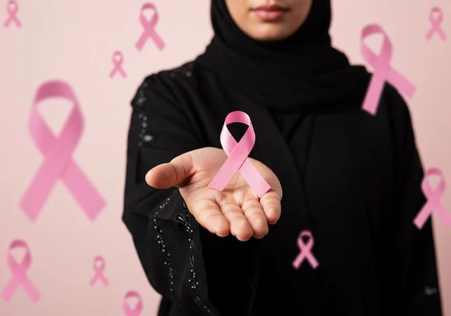 رمز الحملة العالمية، اليوم العالمي للتوعية والكشف المبكر، تحدي الأمراض الخبيثة، بورتريه مقرب لإمرأة عربية خليجي سعودية ترتدي الحجاب والعباءة السوداء وتحمل الشريط الوردي، النظر الى الكاميرا بنظرات القوة، حملة توعوية للكشف المبكر عن سرطان الثدي، خلفية وردية