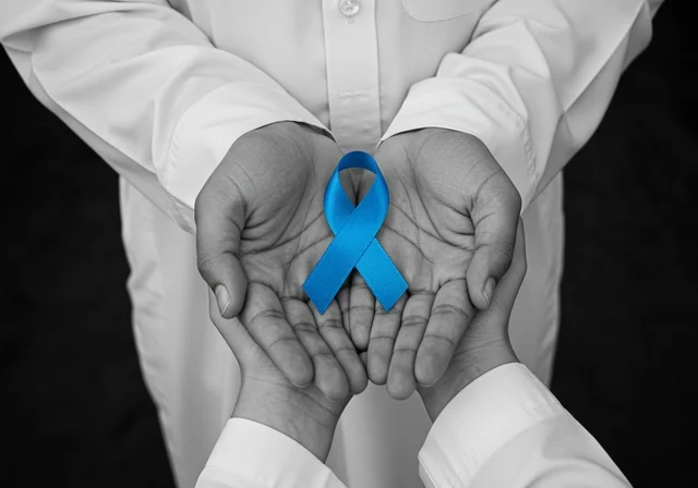 الحفاظ على الصحة الجسدية، شعار الوعي بسرطان البروستاتا ، حملات الإرشاد والتنبيه للكشف المبكر عن سرطان البروستات، بورتريه مقرب لشاب عربي خليجي سعودي يرتدي الزي التقليدي والشماغ يحمل شريط أزرق للتوعية بالأمراض، خلفية سوداء