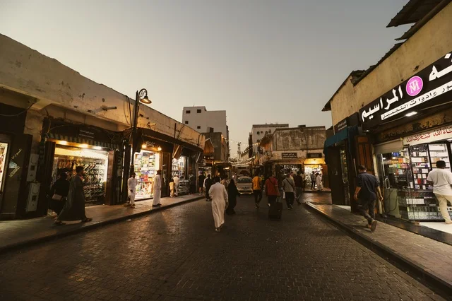 رجال في سوق شعبي يرتدون الزي التقليدي في جدة، المعالم التاريخية في حي البلد، أماكن سياحية تراثية شعبية في المملكة العربية السعودية، الرواشين القديمه في المدينة التاريخية في جدة،  تصميم معماري عربي و إسلامي قديم،  مناطق جذب واستقطاب السياح