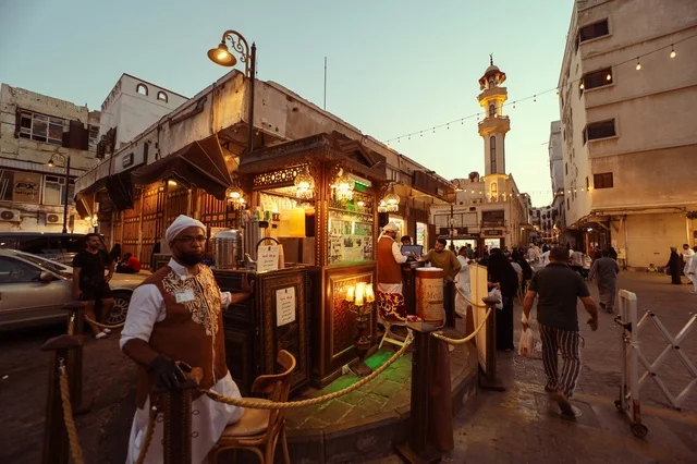 رجال في سوق شعبي يرتدون الزي التقليدي في جدة، المعالم التاريخية في حي البلد، أماكن سياحية تراثية شعبية في المملكة العربية السعودية، الرواشين القديمه في المدينة التاريخية في جدة،  تصميم معماري عربي و إسلامي قديم،  مناطق جذب واستقطاب السياح