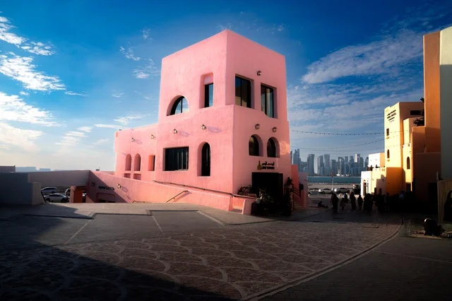 مركز جذب السياح من شتى أنحاء العالم، تصاميم تعكس التراث والتاريخ القطري بألوان مميزة، صورة مقربة لمبنى في ميناء الدوحة القديم في قطر، تعزيز صناعة السياحة البحرية، الفن الهندسي المعماري للمباني والفنادق والشاليهات على شاطئ البحر