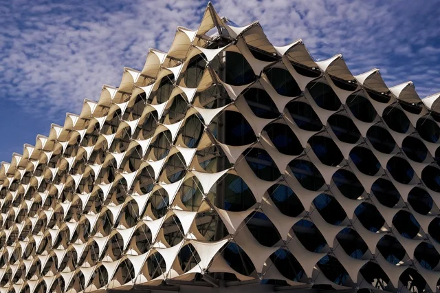 The architectural engineering art of the exterior of King Fahd National Library in Riyadh, green trees and plants, national libraries in the Kingdom of Saudi Arabia, famous cultural landmarks of Riyadh, a close-up image of the architectural engineering art of the exterior of King Fahd Library, tourist attractions in Saudi Arabia.