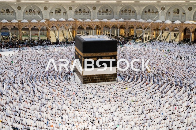Performing the rituals of Hajj and Umrah, worship and drawing closer to God, the qibla of Islam and Muslims, the circumambulation of pilgrims and Umrah performers around the Holy Kaaba in Mecca during the day, the minarets surrounding the sanctuary, the House of God in the Sacred Mosque in the Holy City of Mecca in the Kingdom of Saudi Arabia.