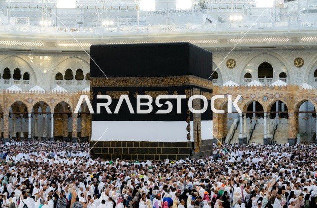 Worship and drawing closer to God, performing the rituals of Hajj and Umrah, the qibla of Islam and Muslims, the circumambulation of pilgrims and Umrah performers around the Holy Kaaba in Mecca during the day, the minarets surrounding the sanctuary, the House of God, the Sacred House in the Holy Mosque in the Kingdom of Saudi Arabia.