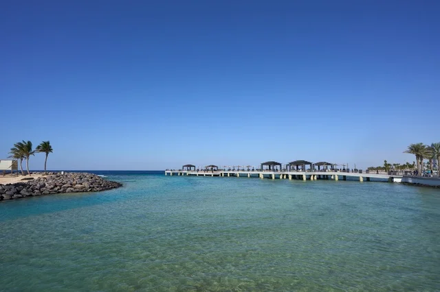The blue color of the sea is a reflection of the clear blue sky, the corniche overlooking the Red Sea coast, attractions for visitors to the coastal city of Jeddah, famous landmarks and tourist places, the waterfront in the Kingdom of Saudi Arabia, the aquatic landscapes, and the interest in planting trees.
