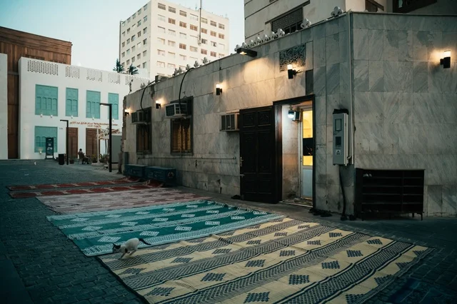 زقاقا في المدينة التاريخية فرش فيها سجادات ملونة بأنماط مختلفة، الرواشين القديمه في جدة، تصميم معماري عربي و إسلامي قديم، البيوت الأثرية في البلد التاريخي في جدة, أماكن سياحية تراثية شعبية في المملكة العربية السعودية، المعالم التاريخية في حي البلد