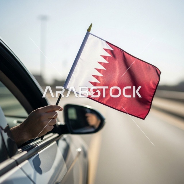 Commemorating the founding of the state, celebrating Qatar National Day on December 18, a close-up image of a Qatari Gulf Arab man's hand inside a car holding the Qatari flag outside with gestures of pride and honor, symbols and national cultures, love for the homeland and belonging to it, an expression of belonging and Qatari identity.