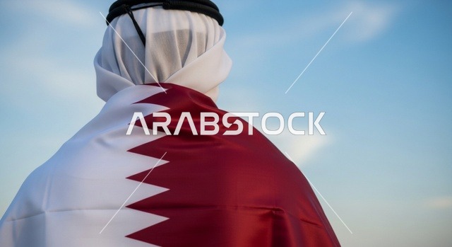 إحياء ذكرى تأسيس الدولة، الاحتفال باليوم الوطني القطري 18 ديسمبر، صورة مقربة لرجل عربي خليجي قطري يقف بثقة وشموخ يضع علم قطرعلى كتفيه بايماءات الفخروالاعتزاز، رموز وثقافات وطنية, حب الوطن والانتماء إليه