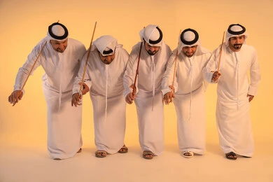 أجواء تراثية تعبّر عن الفخر بالموروث الثقافي الإماراتي،إيقاعات متناغمة وحركات جماعية تعكس روح الوحدة والاعتزاز بالهوية الوطنية،مجموعة من الرجال العرب الخليجيين الإماراتيين يرتدون الكندورة والغترة البيضاء يؤدون رقصة العيالة الشعبية بعصا الخيزران،  الحفاظ على التراث الشعبي في المناسبات الوطنية والاجتماعية.
