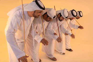 Celebrating national and heritage occasions, performing Emirati folk arts, a portrait of a group of Emirati Gulf Arab men wearing the kandura and ghutrah performing the traditional Ayala dance, gestures of joy and pride in national identity, preserving cultural heritage and authentic customs.