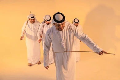 أجواء تراثية تعبّر عن الفخر بالموروث الثقافي الإماراتي،إيقاعات متناغمة وحركات جماعية تعكس روح الوحدة والاعتزاز بالهوية الوطنية،مجموعة من الرجال العرب الخليجيين الإماراتيين يرتدون الكندورة والغترة البيضاء يؤدون رقصة العيالة الشعبية بعصا الخيزران،  الحفاظ على التراث الشعبي في المناسبات الوطنية والاجتماعية.