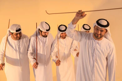 الاحتفال بالمناسبات الوطنية والتراثية، أداء الفنون الشعبية الإماراتية، بورترية لمجموعة من الرجال العرب الخليجيين الإماراتيين يرتدون الكندورة والغترة يقومون بعرض رقصة العيالة التراثية، إيماءات السرور والفخر بالهوية الوطنية، الحفاظ على الموروث الثقافي والعادات الأصيلة