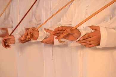 الفخر بالعادات والتقاليد الإماراتية، إيقاعات متناغمة وحركات جماعية تعكس روح الوحدة والاعتزاز بالهوية الوطنية،مجموعة من الرجال العرب الخليجيين الإماراتيين يرتدون الكندورة والغترة البيضاء يؤدون رقصة العيالة الشعبية بعصا الخيزران،  الحفاظ على التراث الشعبي في المناسبات الوطنية والاجتماعية.