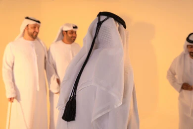 أجواء تراثية تعبّر عن الفخر بالموروث الثقافي الإماراتي،إيقاعات متناغمة وحركات جماعية تعكس روح الوحدة والاعتزاز بالهوية الوطنية،مجموعة من الرجال العرب الخليجيين الإماراتيين يرتدون الكندورة والغترة البيضاء يؤدون رقصة العيالة الشعبية بعصا الخيزران،  الحفاظ على التراث الشعبي في المناسبات الوطنية والاجتماعية.